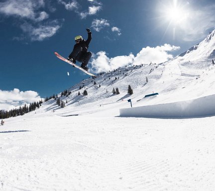 Dieses Bild zeigt einen Snowboarder der im Snowpark am Stubnerkogel über eine Rampe springt und dabei einen Stunt in der Luft macht