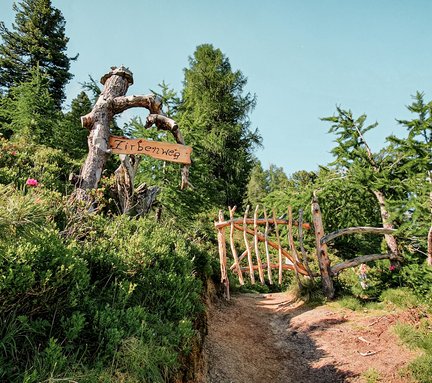 Dieses Bild zeigt ein Tor aus Holz und ein Schild mit der Aufschrift "Zirbenweg"