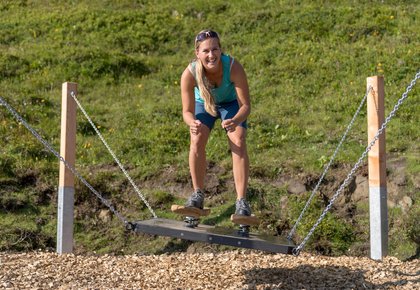 Dieses Bild zeigt eine Frau, die eine Übung im Motorikweg auf der Schlossalm macht
