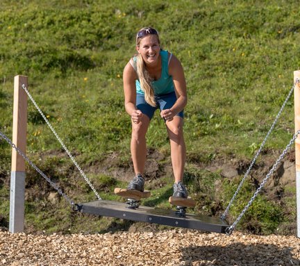 Dieses Bild zeigt eine Frau, die eine Übung im Motorikweg auf der Schlossalm macht