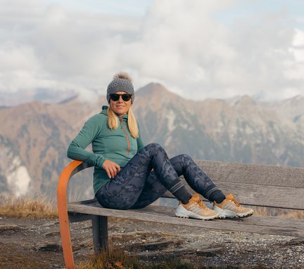 Dieses Bild zeigt eine Frau, die auf einer Bank in Gastein im Herbst sitzt