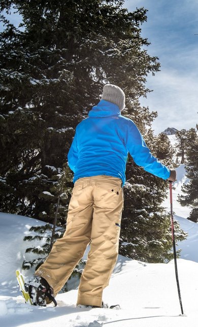 Schneeschuhwanderer stapft durch den verschneiten Wald am Graukogel