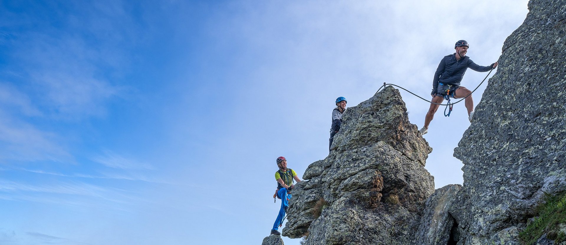 Dieses Bild zeigt eine Gruppe, die auf der Schlossalm auf einem felsigen Klettersteig in luftiger Höhe klettert