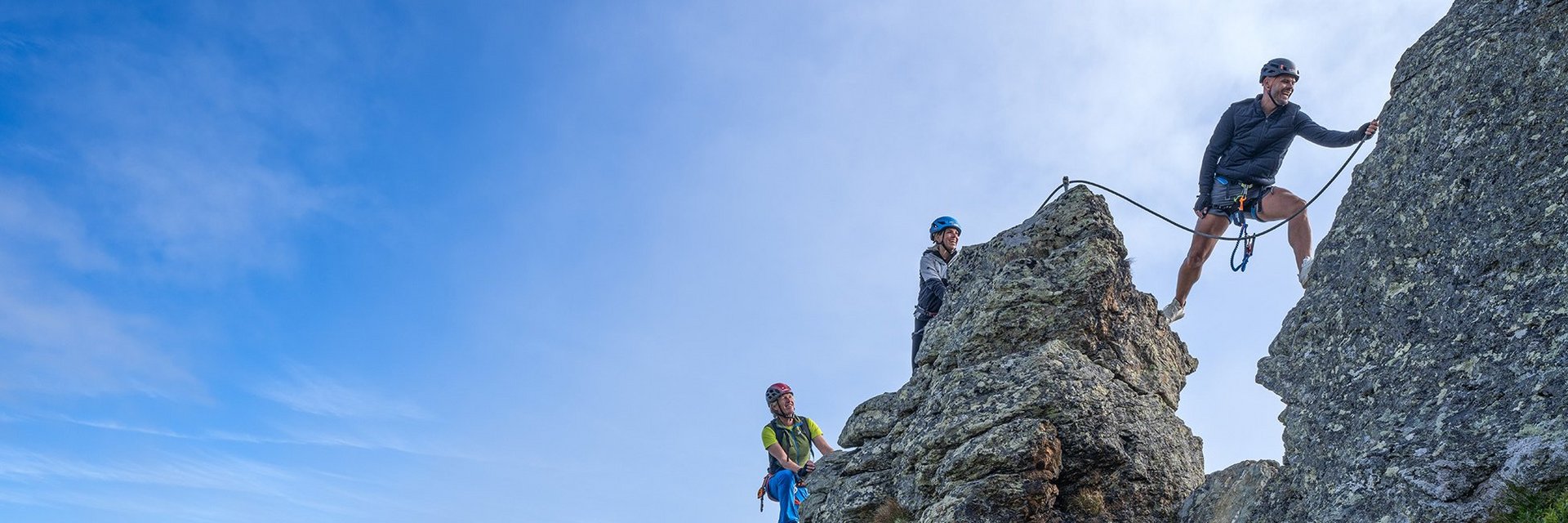 Dieses Bild zeigt eine Gruppe, die auf der Schlossalm auf einem felsigen Klettersteig in luftiger Höhe klettert
