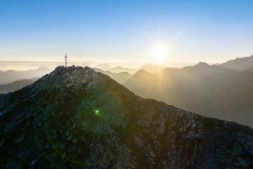 Dieses Bild zeigt den Graukogel mit Gipfelkreuz bei abendlicher Stimmung