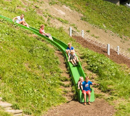 Dieses Bild zeigt eine Gruppe von Kindern, die auf einer Rutsche auf der Schlossalm gemeinsam rutschen