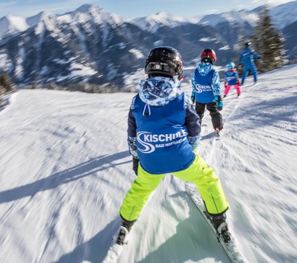 Dieses Bild zeigt eine Gruppe von Skischülern, die dem Skilehrer nachfährt