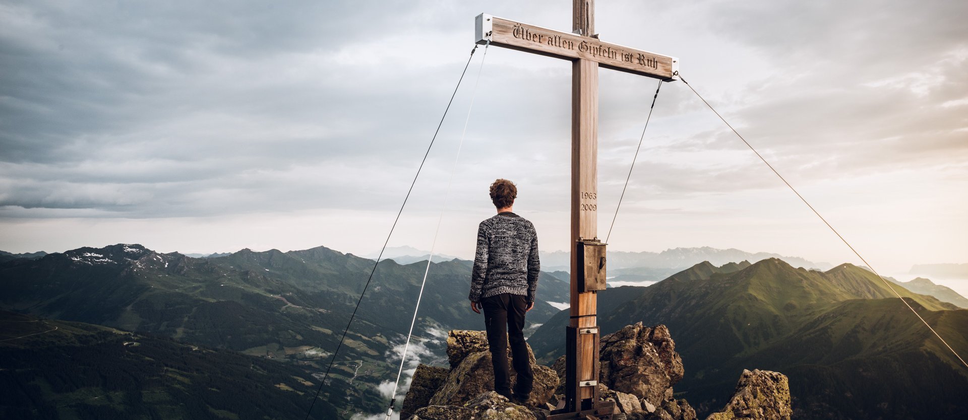 Dieses Bild zeigt einen in die Ferne blickenden Wanderer auf dem Gipfel des Graukogels
