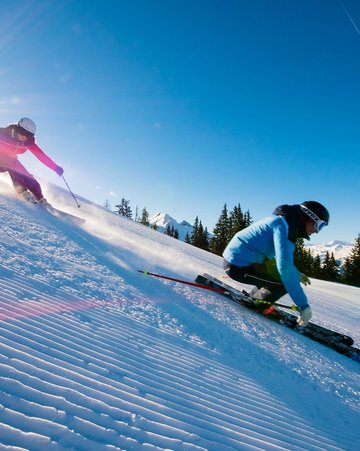 2 Skifahrer beim Early Morning Skiing auf der Piste in Dorfgastein
