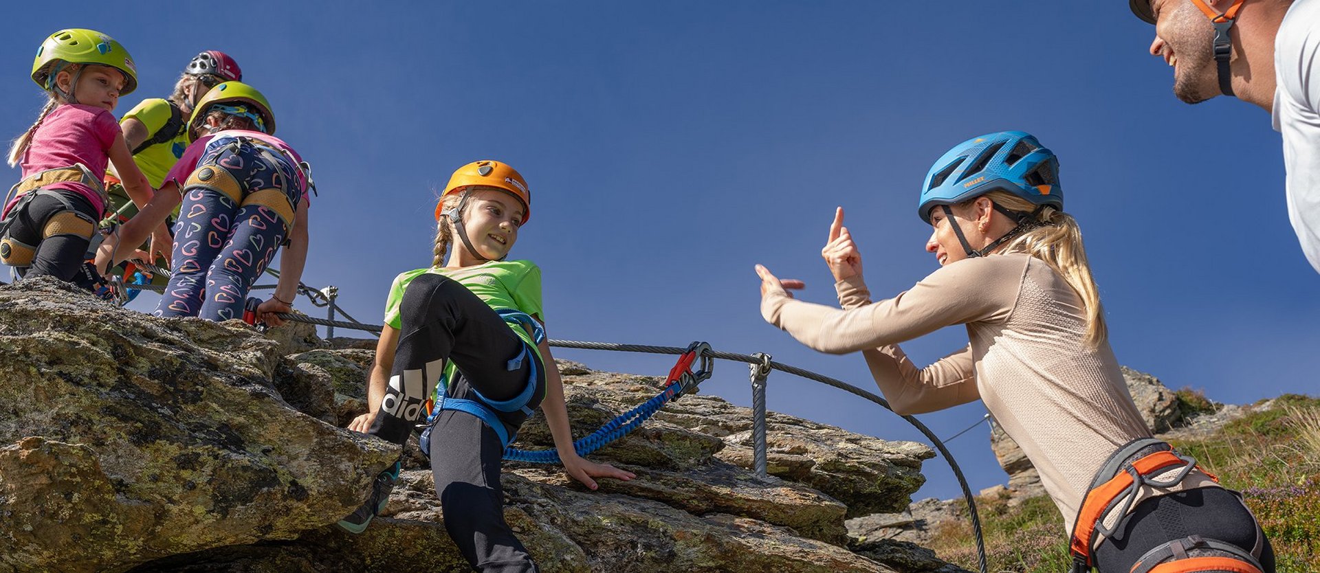 Eine Familie beim gesicherten Klettern am Übungsklettersteig auf der Schlossalm.