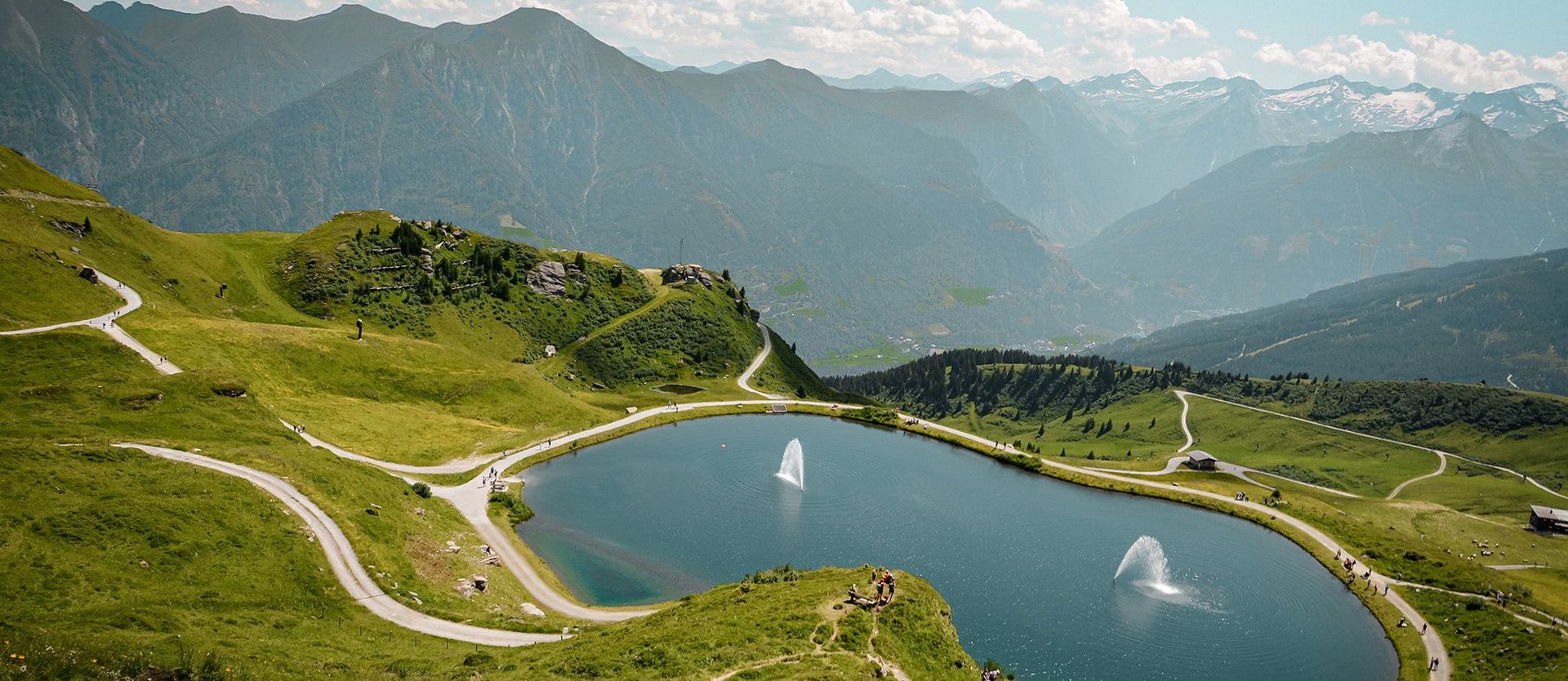 Dieses Bild zeigt eine Luftaufnahme von dem Schlossalmsee mit zwei Wasserfontänen