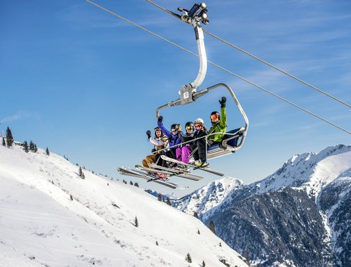 Dieses Bild zeigt eine Gruppe von Skifahrern, die auf einem Sessellift in Gastein sitzen