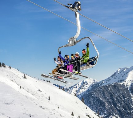 Dieses Bild zeigt eine Gruppe von Skifahrern, die auf einem Sessellift in Gastein sitzen