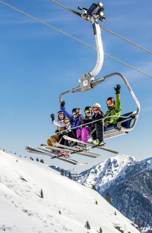 Dieses Bild zeigt eine Gruppe von Skifahrern, die auf einem Sessellift in Gastein sitzen