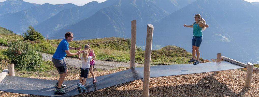 Dieses Bild zeigt eine Familie, die auf einem Trampolin Steg auf der Schlossalm springt