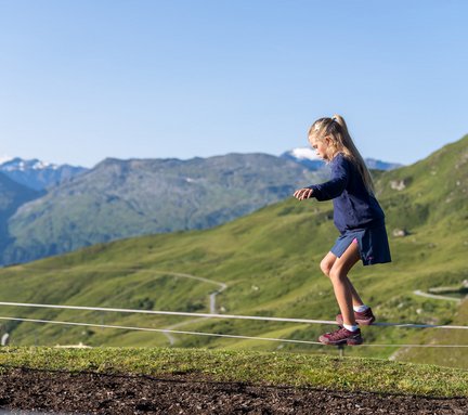 Dieses Bild zeigt ein Mädchen auf einer Slackline im Motorikpark auf der Schlossalm