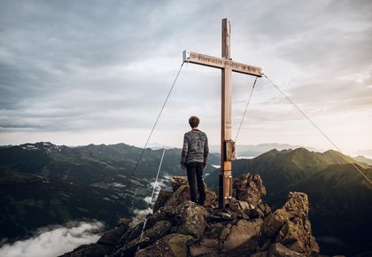 Dieses Bild zeigt einen in die Ferne blickenden Wanderer auf dem Gipfel des Graukogels