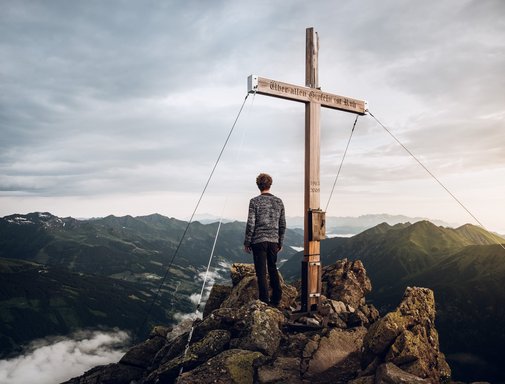 Dieses Bild zeigt einen in die Ferne blickenden Wanderer auf dem Gipfel des Graukogels