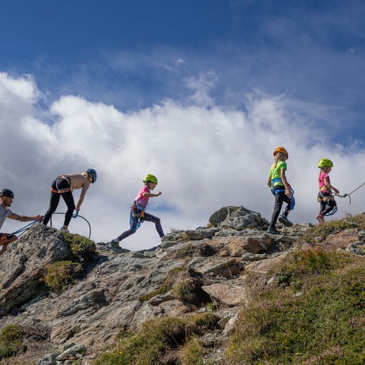 Dieses Bild zeigt eine Familie mit Kindern, die einen Klettersteig auf der Schlossalm absolviert.