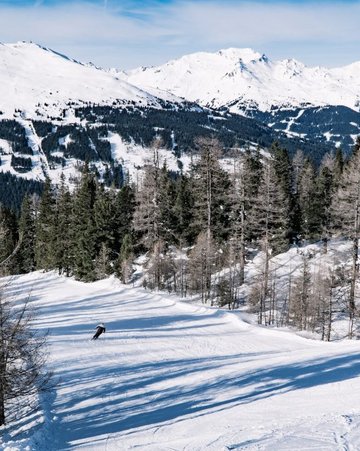 Die Skiabfahrt am Graukogel mit Ausblick auf die verschneiten Berge