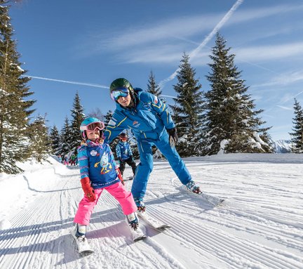 Dieses Bild zeigt eine Skilehrer, der einem Skischulking beim fahren hilft