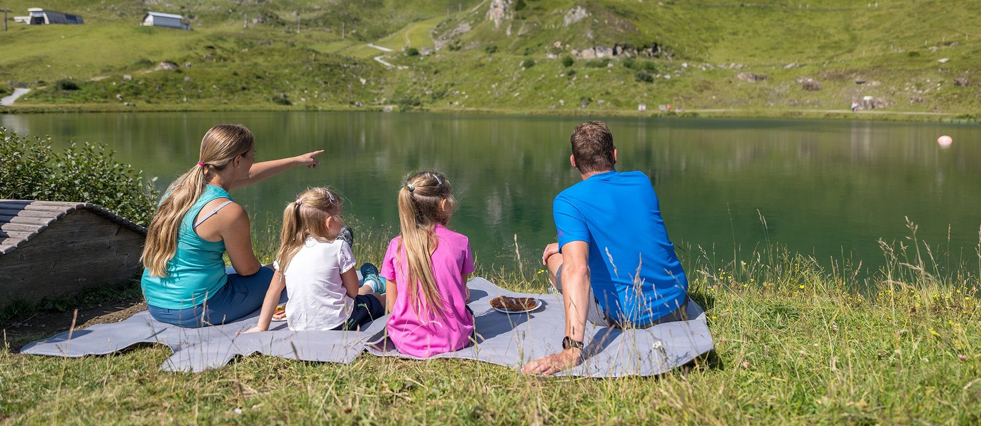 Dieses Bild zeigt eine Familie , die am Schlossalmsee picknickt und in die Ferne sieht
