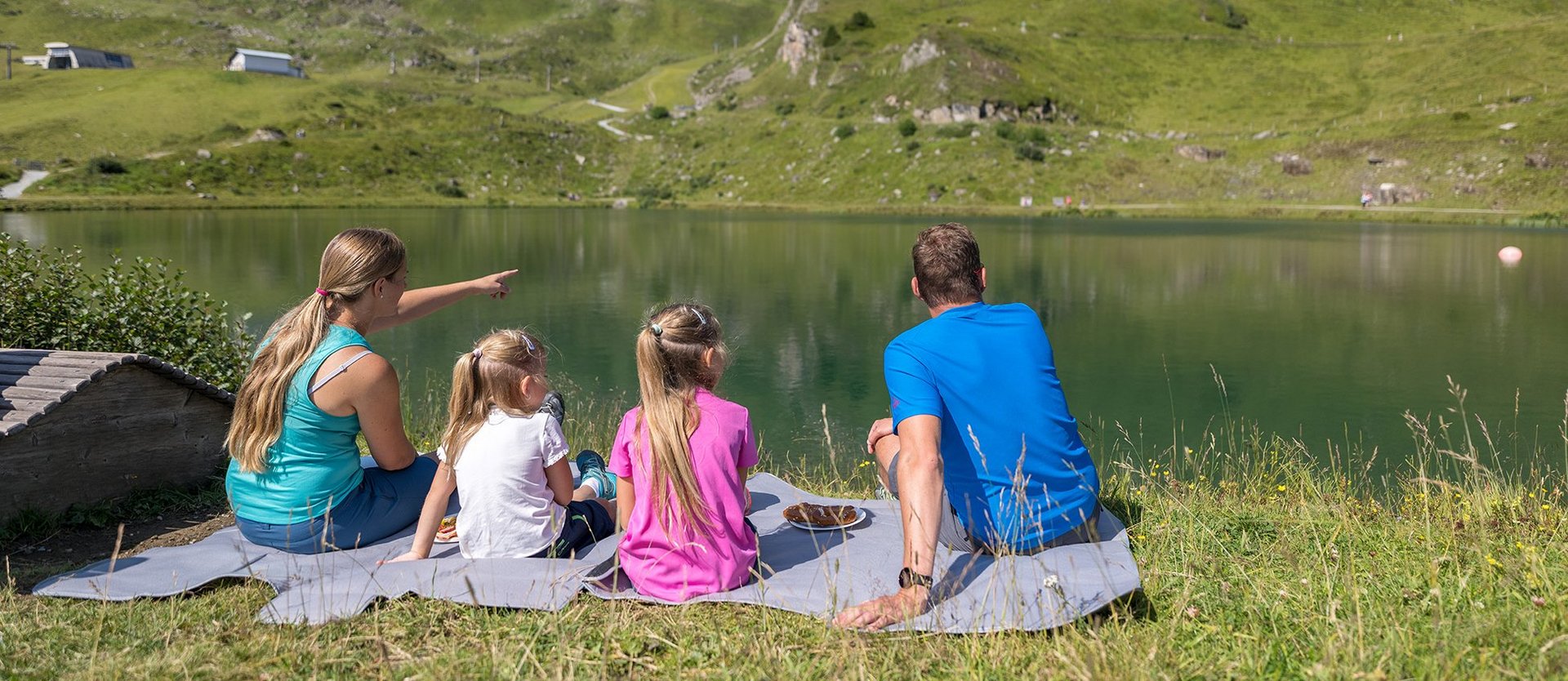 Dieses Bild zeigt eine Familie , die am Schlossalmsee picknickt und in die Ferne sieht