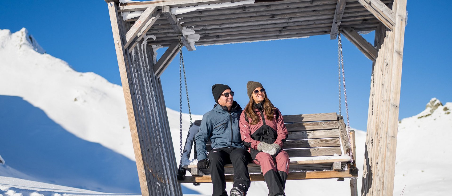 Dieses Bild zeigt ein Paar, dass in einer Hängeschaukel auf der Schlossalm im Winter sitzt