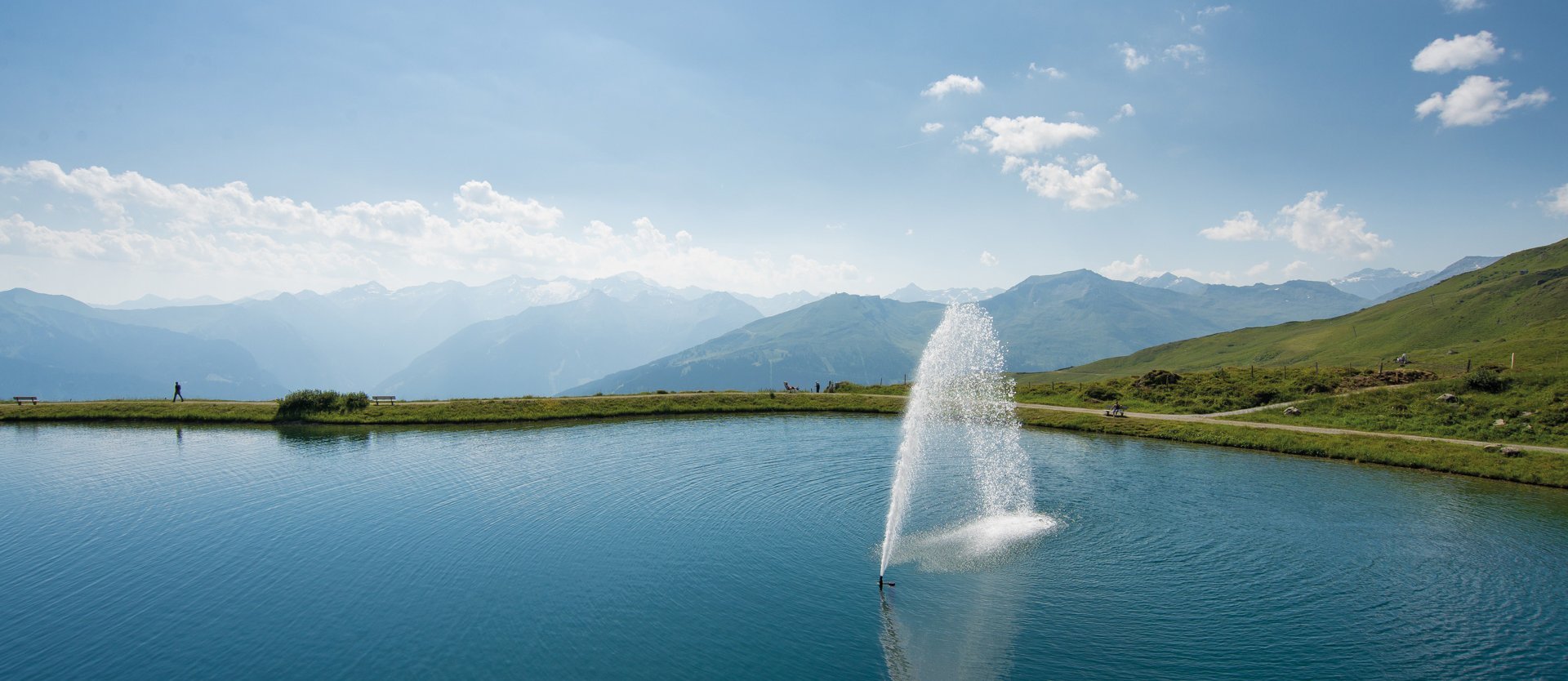 Dieses Bild zeigt den Schlossalmsee mit einer Wasserfontäne in der Mitte