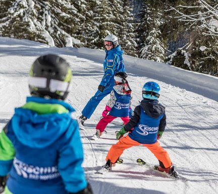 Dieses Bild zeigt Skischulkinder, die dem Skilehrer nachfahren
