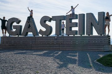 Dieses Bild zeigt eine Familie, die auf der Schlossalm vor dem Gasteinschild posiert