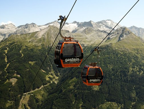Dieses Bild zeigt zwei Gondeln der Stubnerkogelbahn mit einem sommerlichen Bergpanorama im Hintergrund