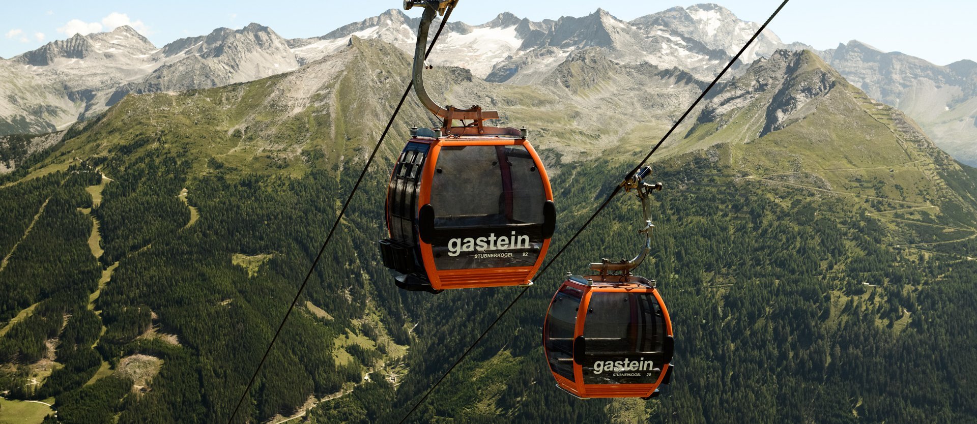Dieses Bild zeigt zwei Gondeln der Stubnerkogelbahn mit einem sommerlichen Bergpanorama im Hintergrund