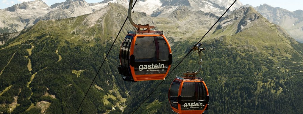 Dieses Bild zeigt zwei Gondeln der Stubnerkogelbahn mit einem sommerlichen Bergpanorama im Hintergrund