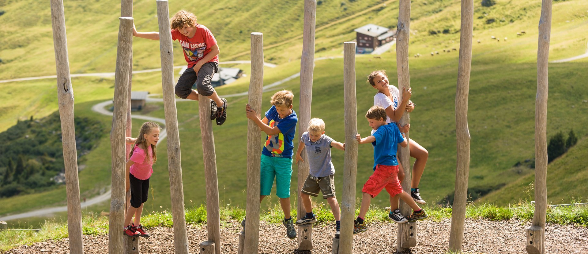 Dieses Bild zeigt eine Gruppe von Kindern, die in einen Pacour aus Baumstämmen klettert