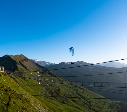 Dieses Bild zeigt einen Paragleiter, der am Stubnerkogel bei der Hängebrücke fliegt