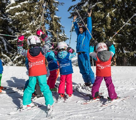 Dieses Bild zeigt eine Gruppe von Skischülern, die auf der Piste stehen mit einem Skilehrer